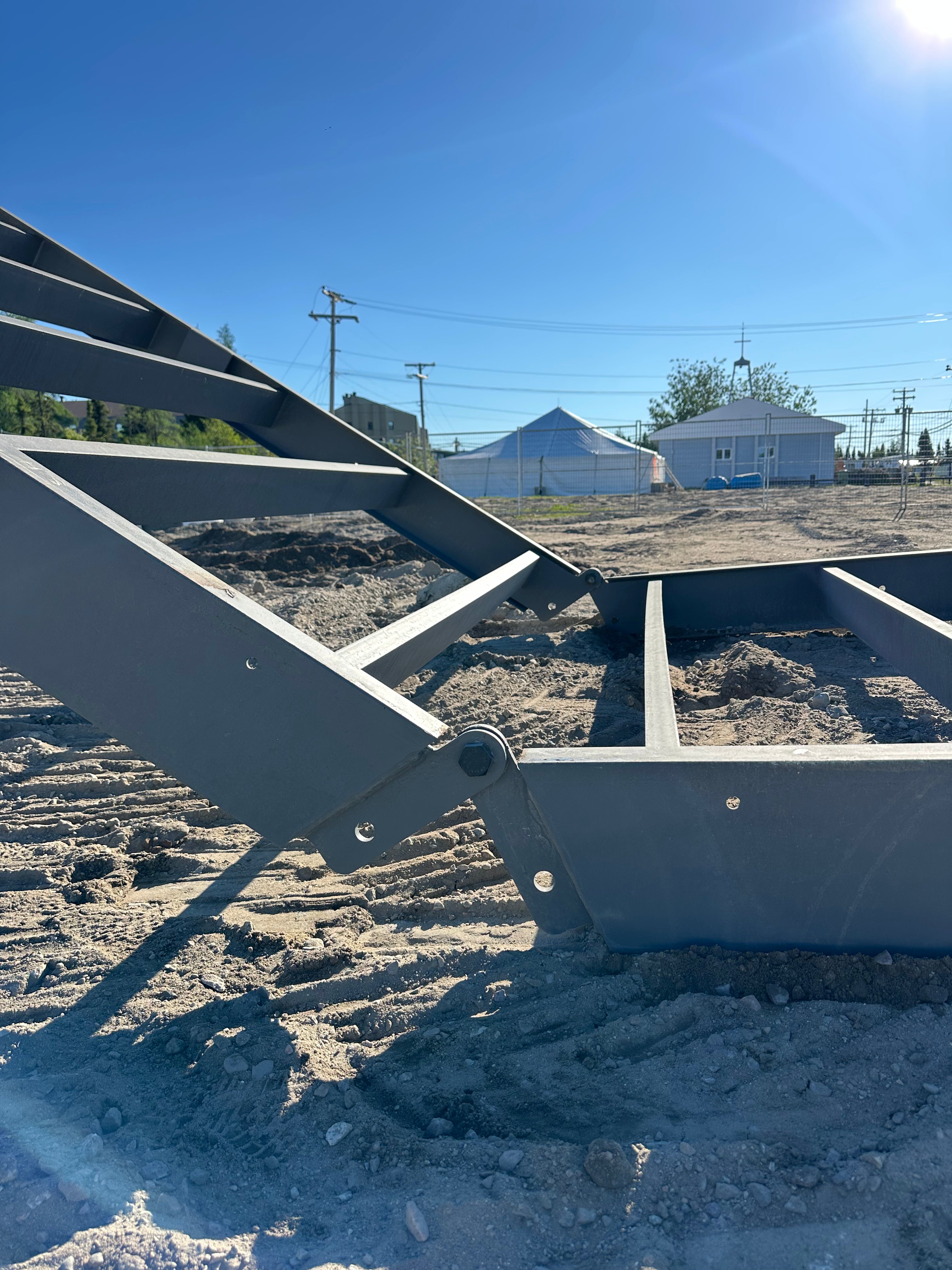 Metal staircase leading to a raised platform with a clear blue sky and houses in the background.