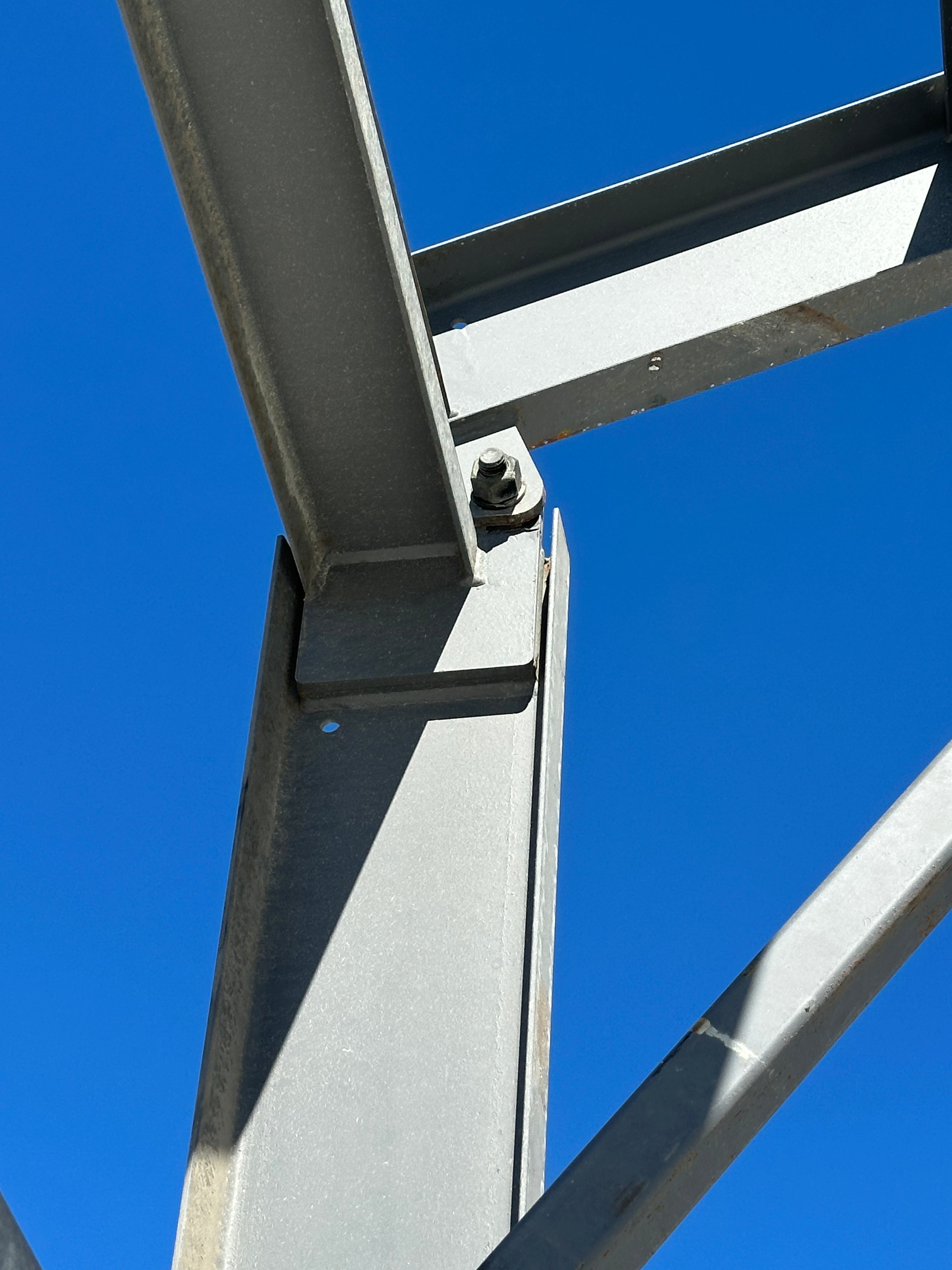 Metal frame structure with a bolt against a clear blue sky