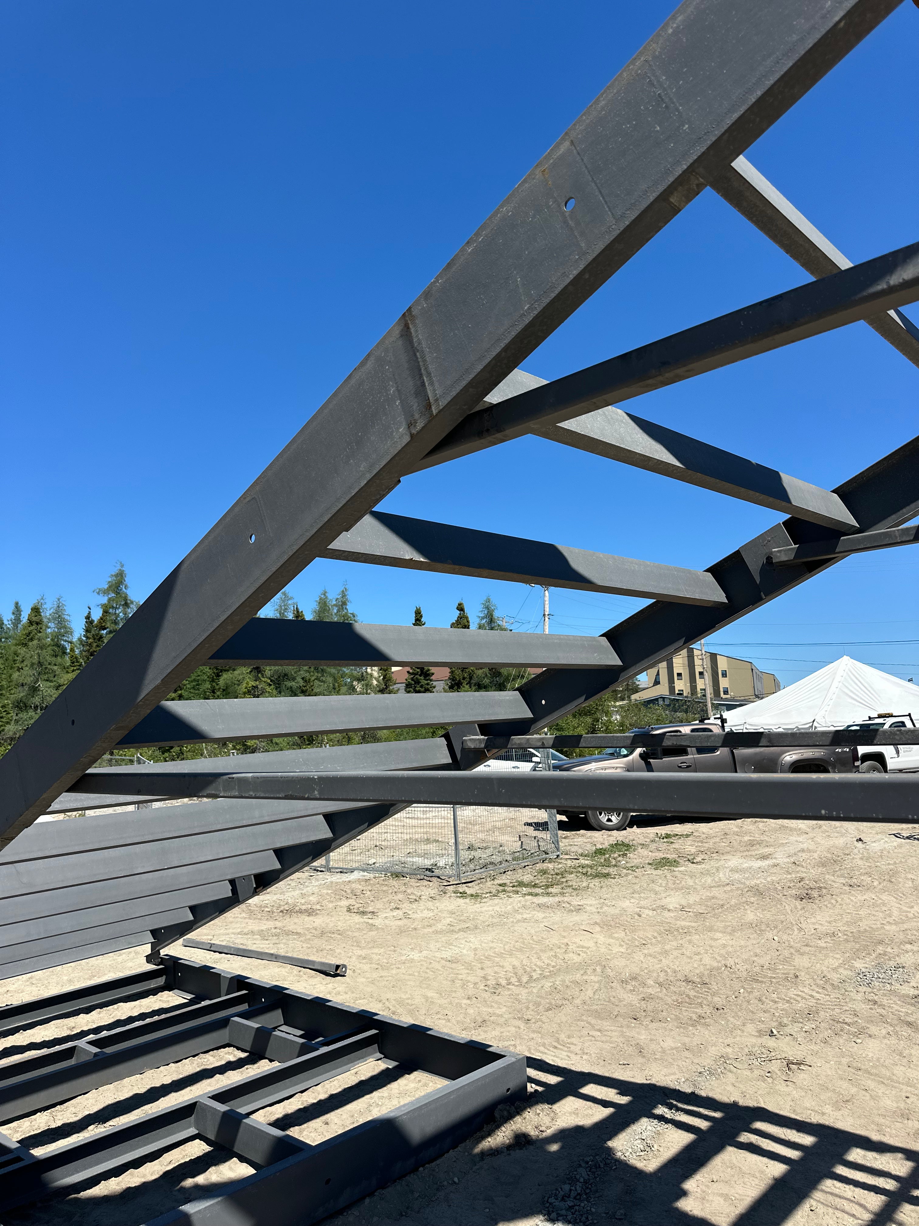 Metal frame structure with a clear blue sky and distant buildings in the background