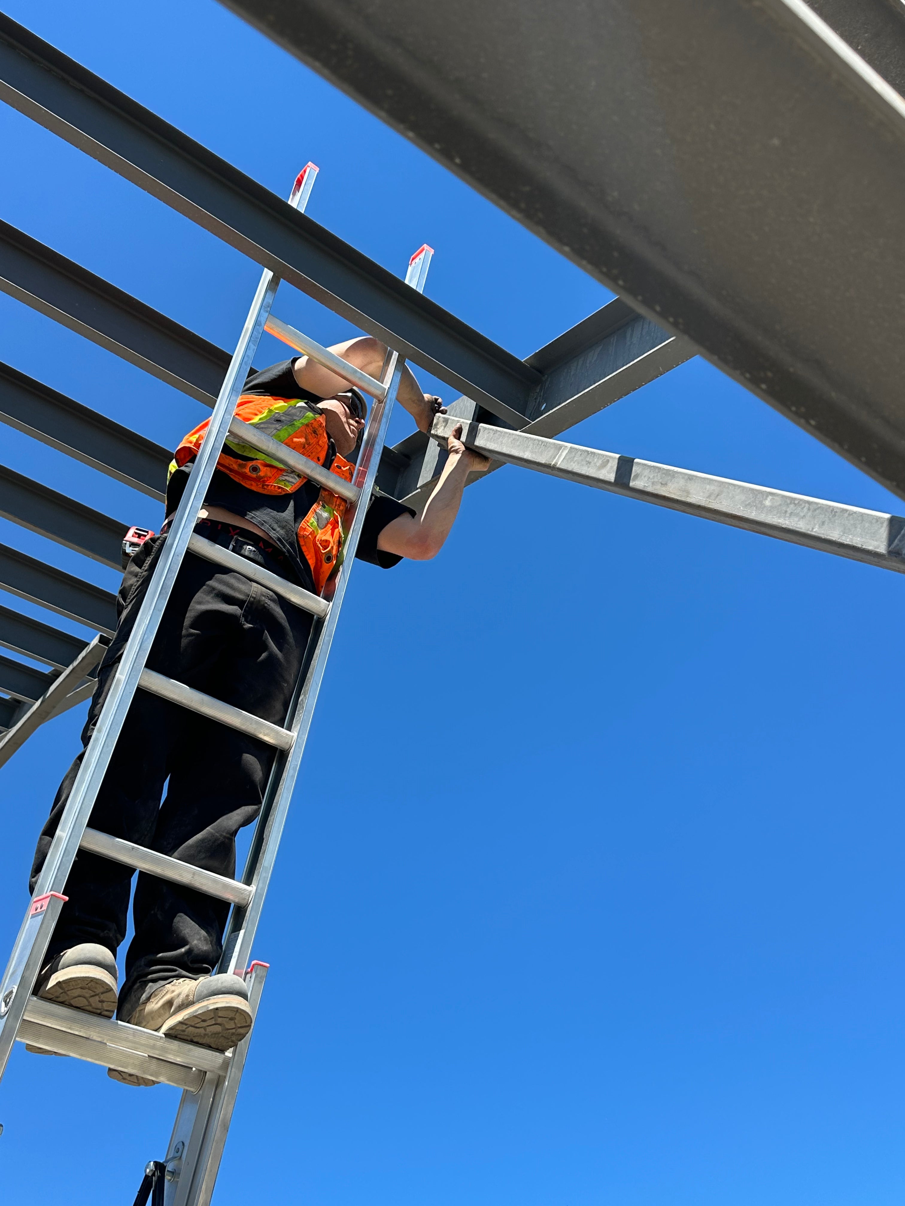 Person on a ladder against a clear blue sky