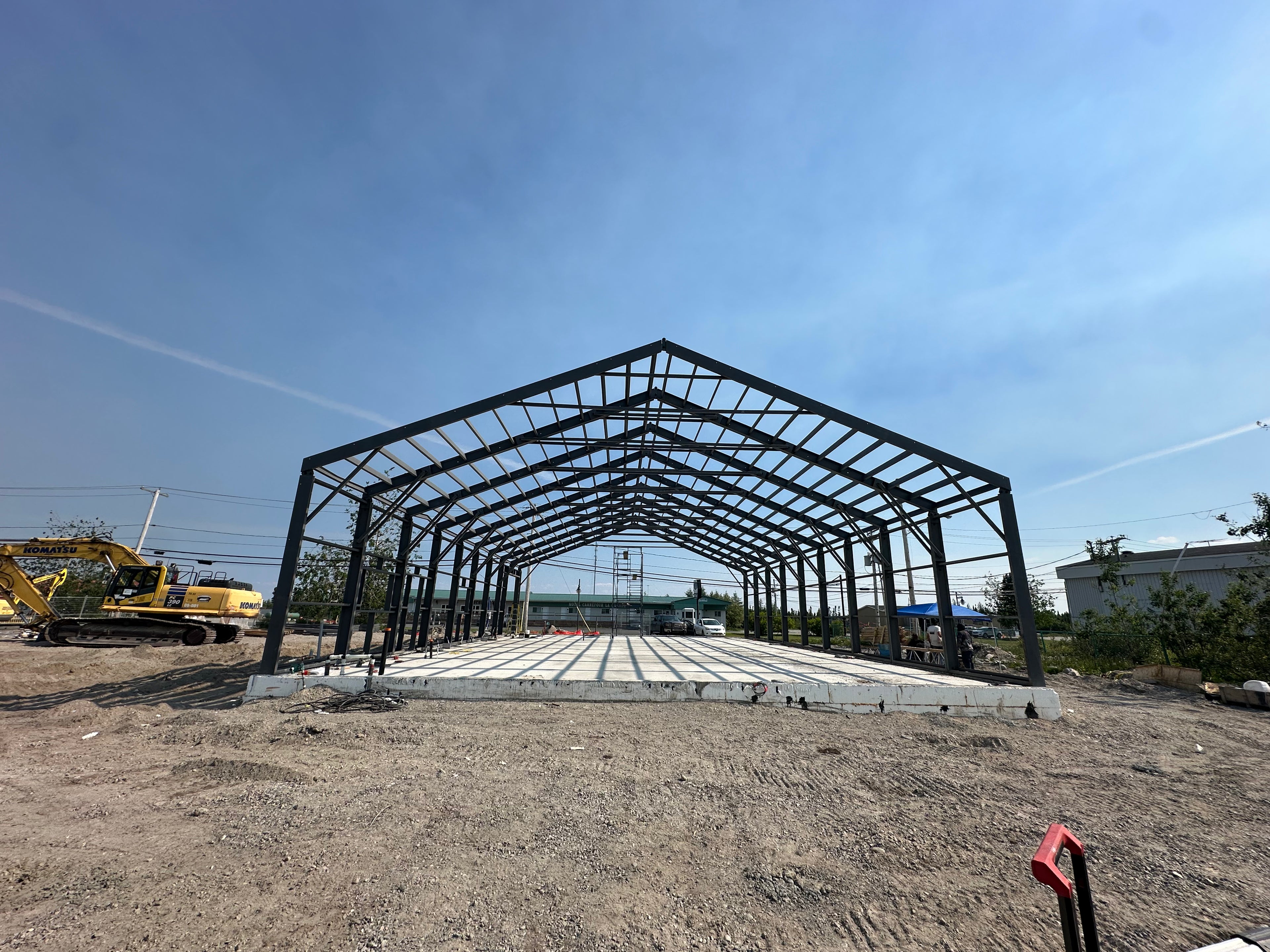 Under construction metal building frame with blue sky and equipment in the background