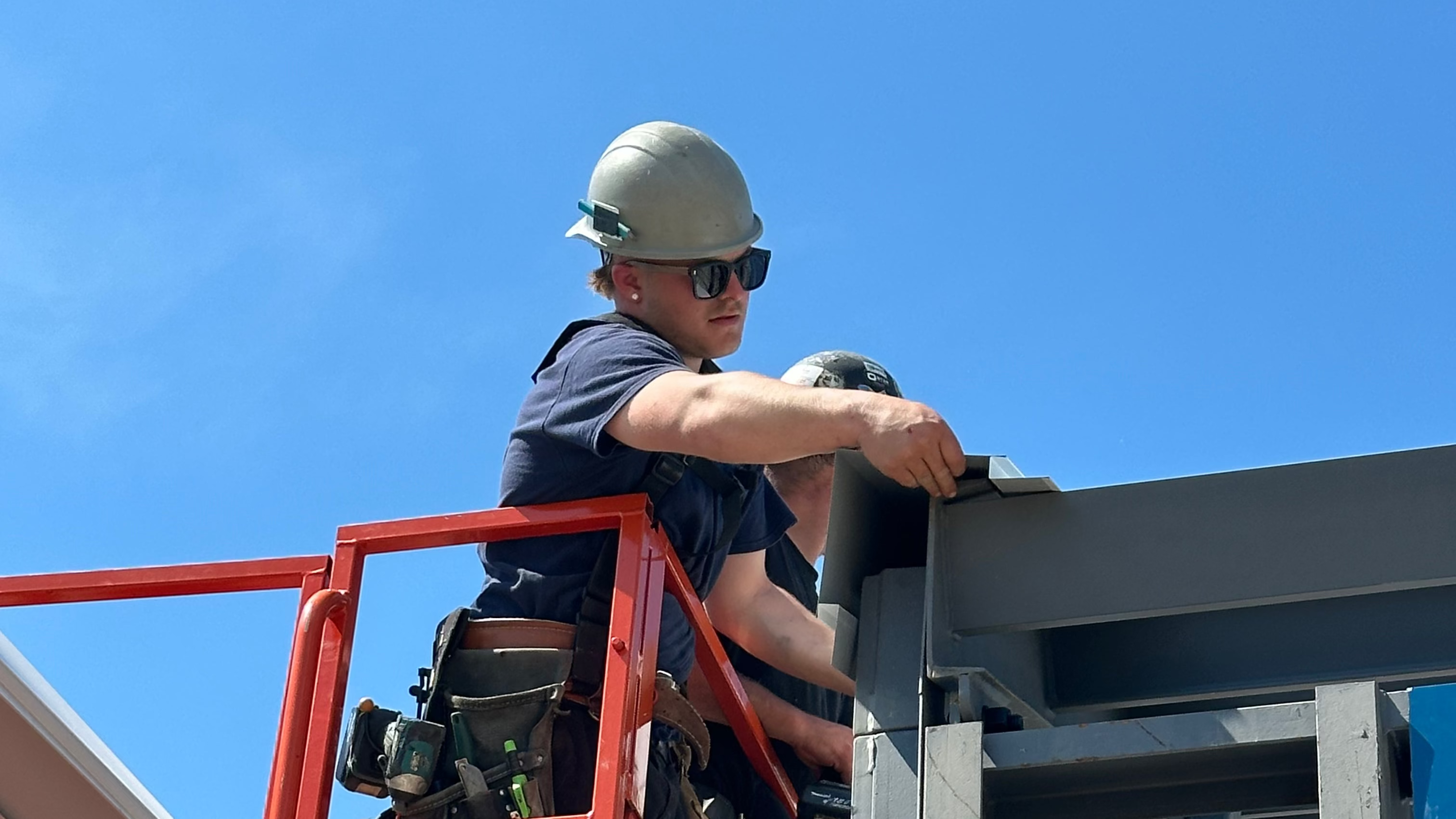 Person on a red scaffolding platform against a clear blue sky